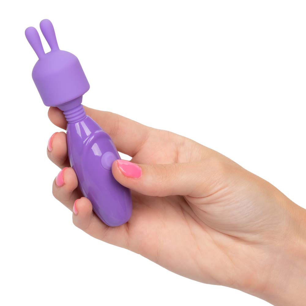 Hand holding purple vibrating massage device.