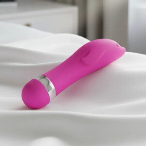 Pink dolphin-shaped vibrator on white fabric.