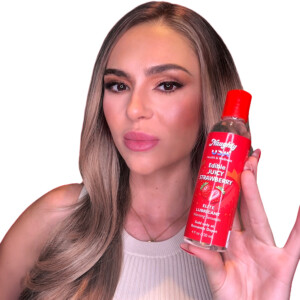 Woman holding Naughty USA edible lubricant bottle.