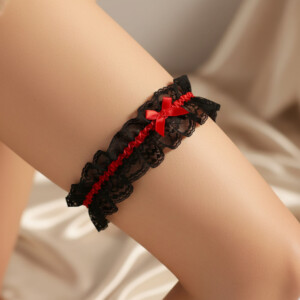 Black lace garter with red ribbon on leg.