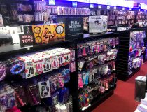 Romantic Depot Manhattan adult toy section featuring shelves stocked with vibrators, dildos, and other intimate products, arranged in an organized retail display.