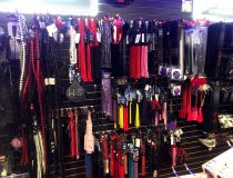 Bondage gear display at Romantic Depot Manhattan featuring handcuffs, whips, blindfolds, and beginner BDSM kits.