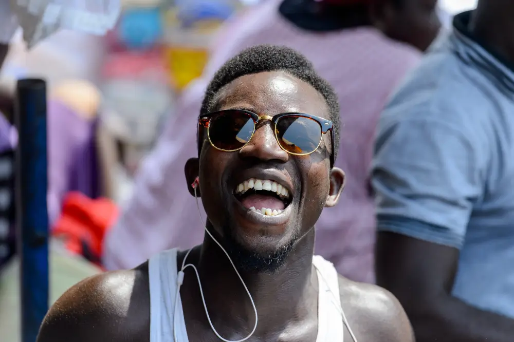 Smiling Black man in sunglasses enjoying a Pride or Juneteenth celebration outdoors, expressing joy, freedom, and self-expression.