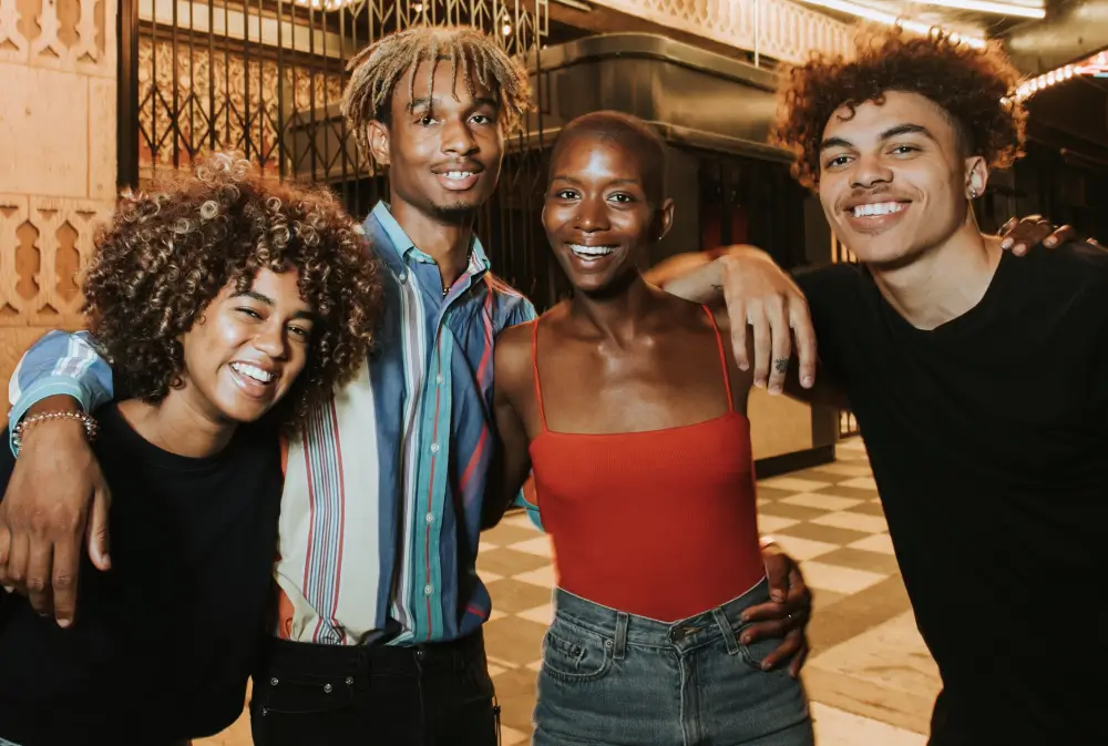 Group of young Black adults smiling and embracing each other while celebrating Juneteenth at night in New York City.