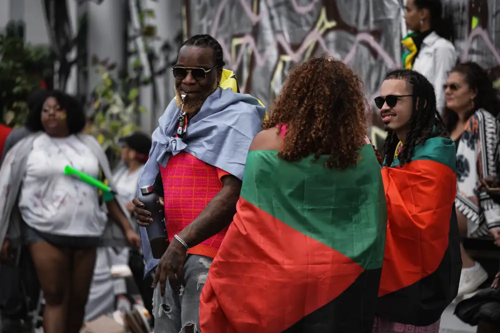 People wrapped in Pan-African flags celebrating Juneteenth 2025 at a public event, honoring Black freedom and cultural pride.