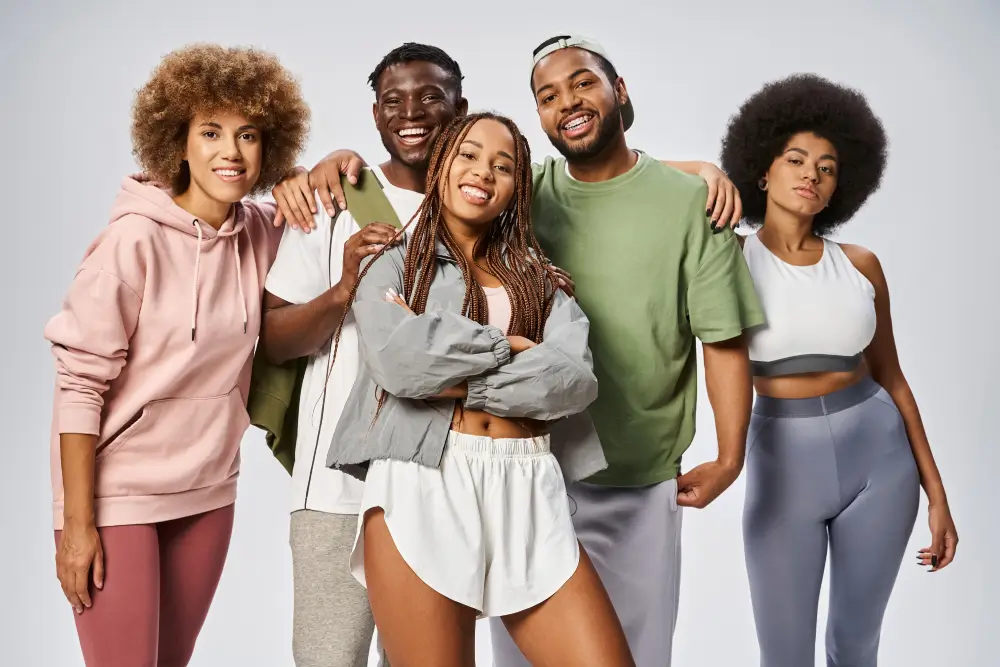 Group of confident young Black adults smiling and posing together, representing unity, empowerment, and inclusive self-expression for Juneteenth and Pride Month.