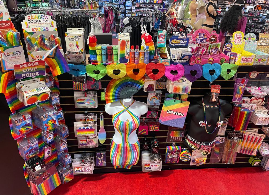 Pride-themed display at Romantic Depot featuring rainbow lingerie, LGBTQ+ accessories, novelty candy, and colorful adult products