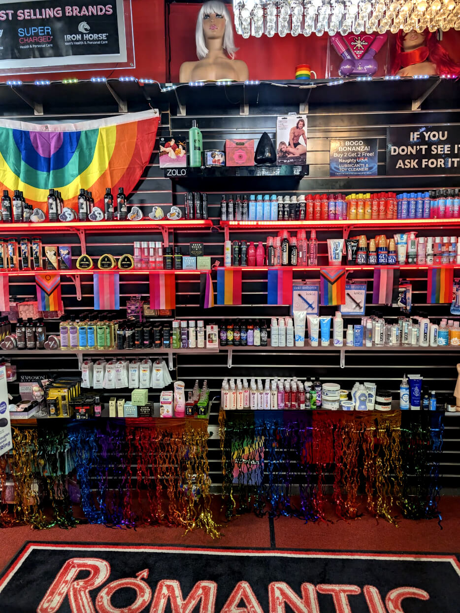 LGBTQ+ Pride-themed display at Romantic Depot NYC featuring inclusive lubes, toys, rainbow flags, and sexual wellness products.