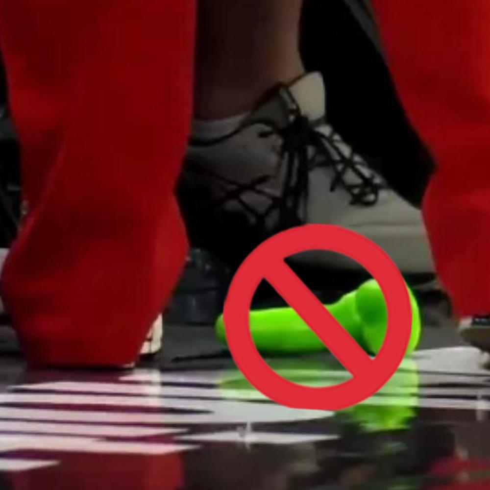 Green sex toy on WNBA court with a red prohibition symbol, highlighting safety concerns